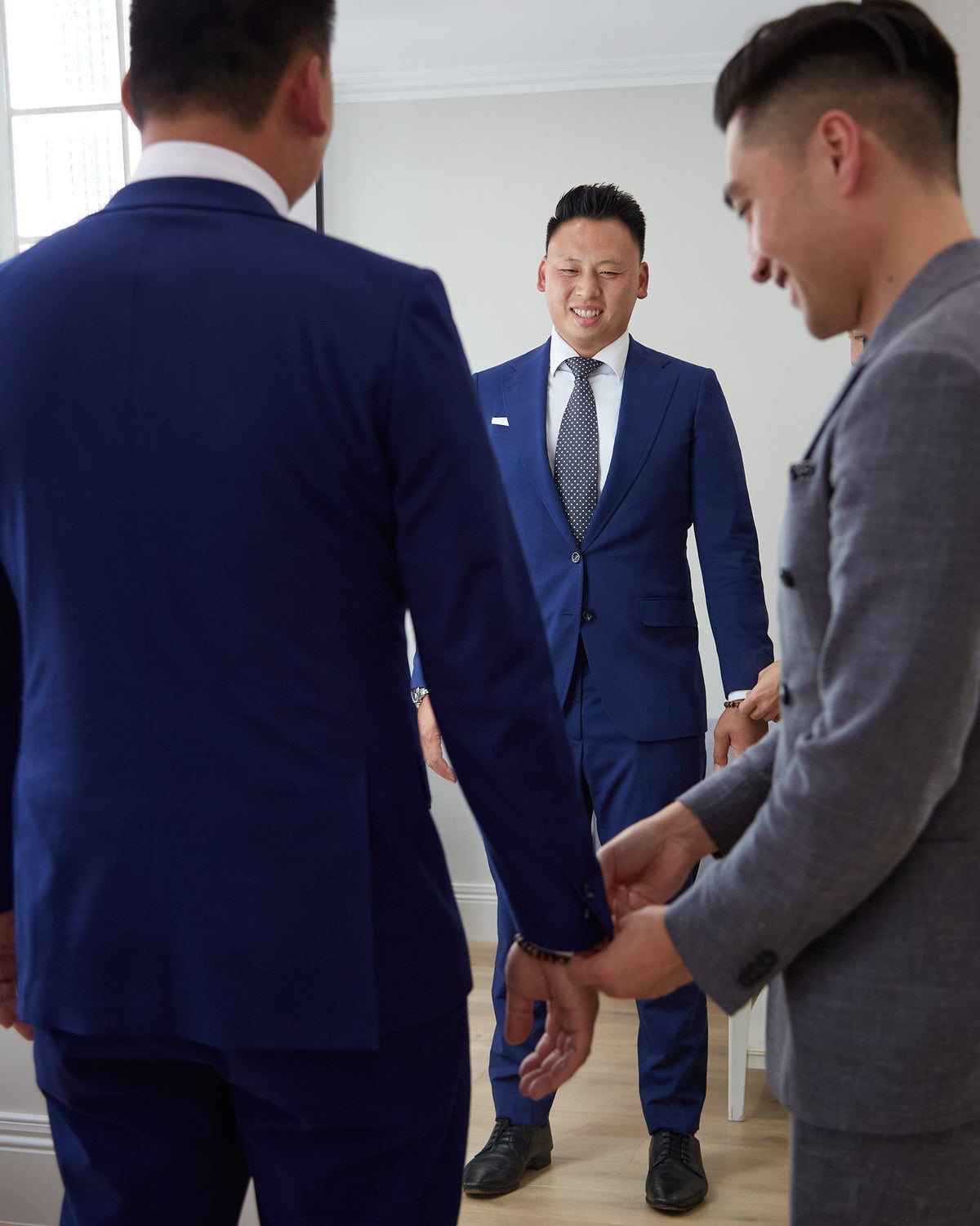 Fitting in progress: a stylist adjusts the sleeve of a client's navy suit