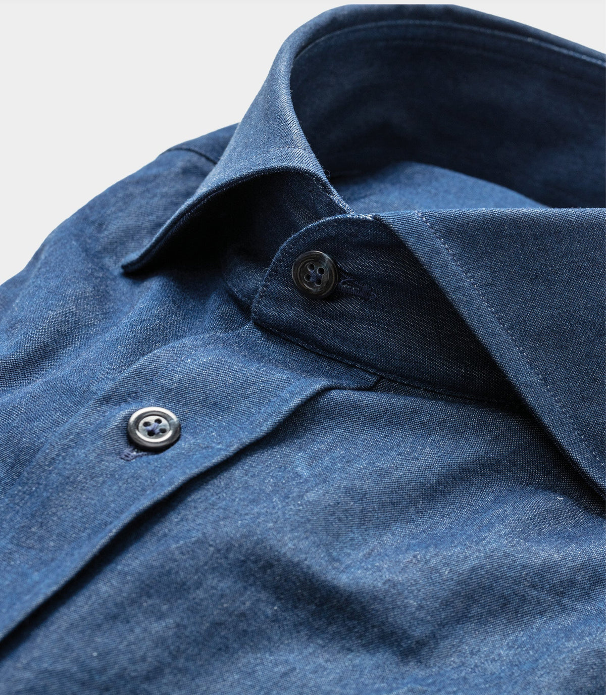 Close-up of the collar and front button of an indigo shirt