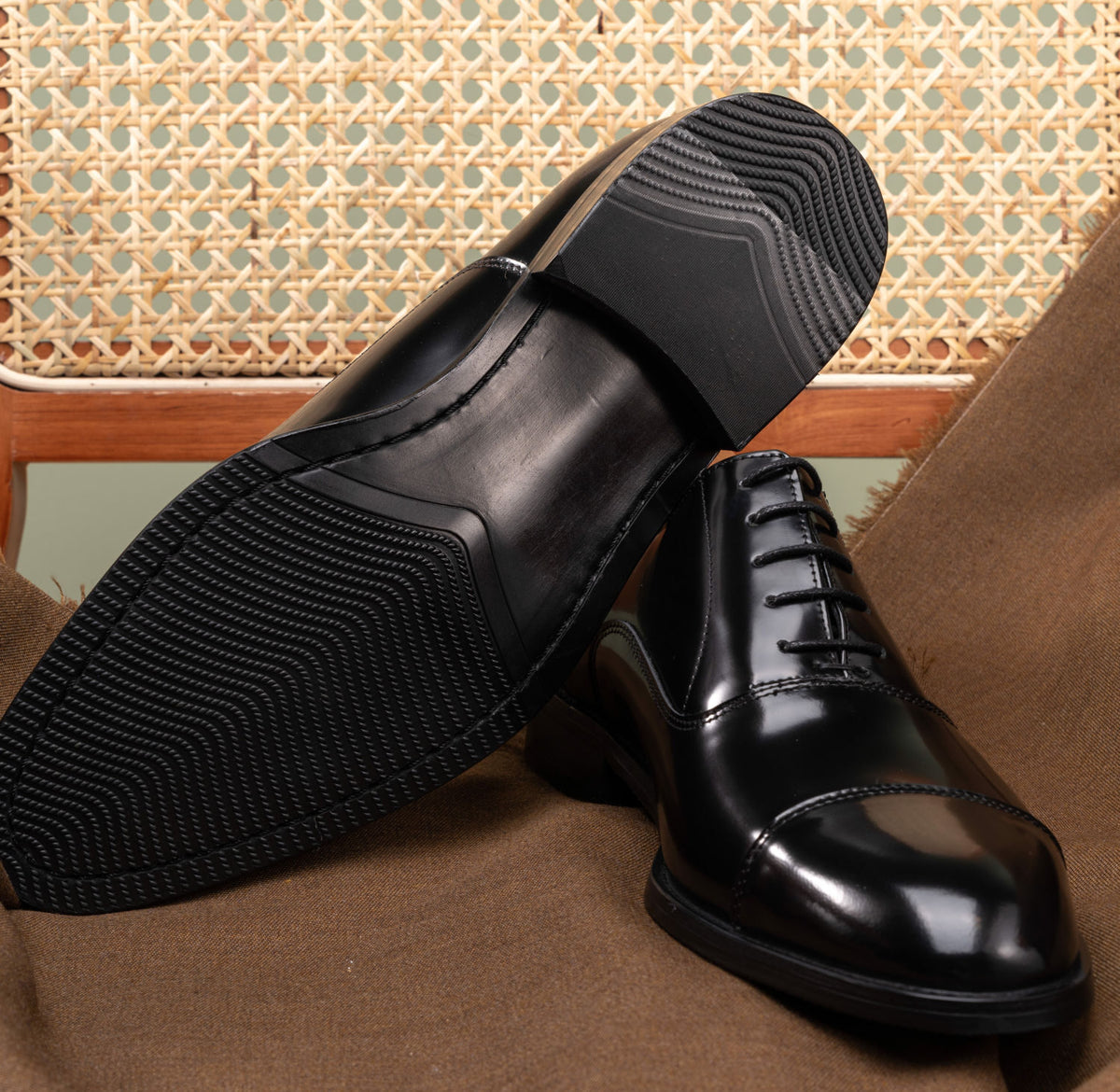 The Haider Black Patent Leather Oxford pair, one shoe propped to show the sole