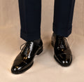 The Haider Black Patent Leather Oxford worn on a model's feet, front view