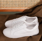 Zante White Sneaker pair displayed on a brown fabric surface with a woven cane backdrop