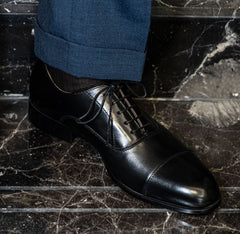 The Haider Black Leather Oxford worn on a model's foot with a cuffed trouser