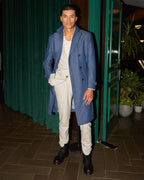 Grey Jersey Stretch Suit with its overcoat, standing at a night-time doorway, hand in pocket