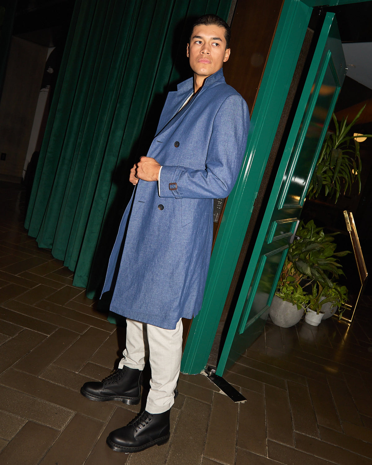 Urban Denim Trench Coat, standing at a night-time doorway with a hand in the pocket