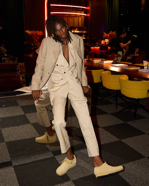 Cream Couture Suit with a houndstooth blazer, model standing in the same lounge setting