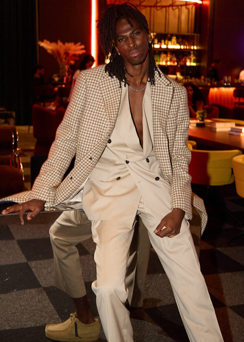 Cream Couture Suit with a houndstooth blazer worn open, model seated in a lounge