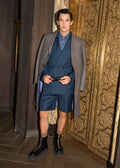 Fast Break Tailored Set with an overcoat, model adjusting the belt buckle at a gold doorway