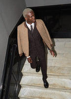 The Brown Capper Three Piece worn with a check overcoat, model descending a marble staircase