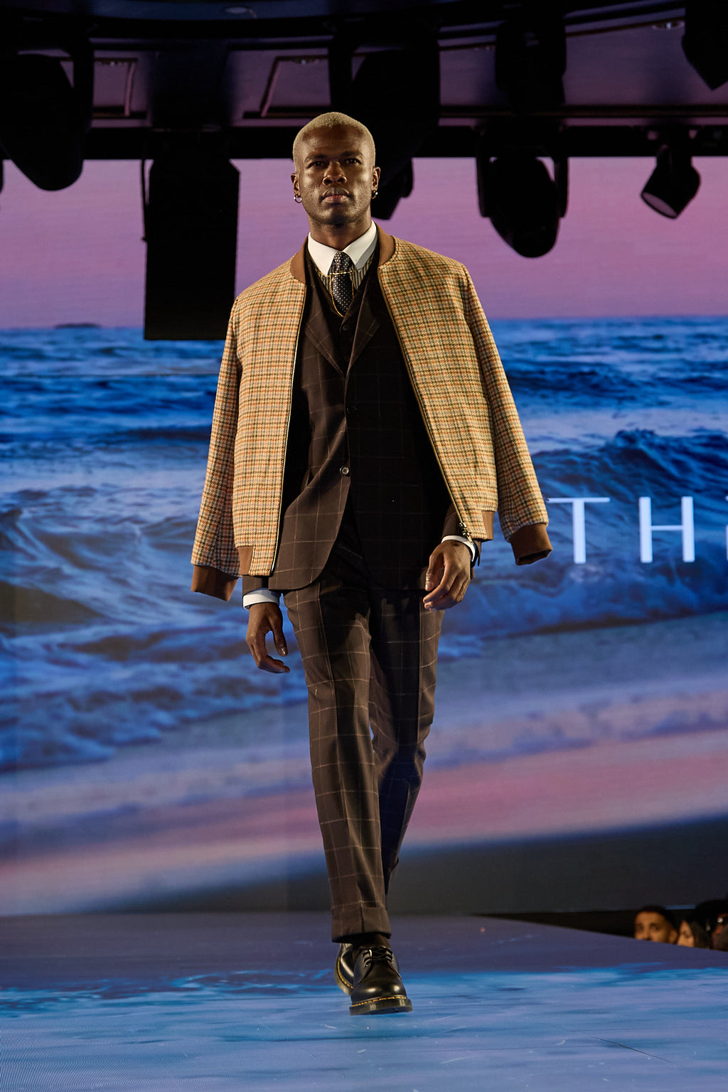 The Brown Capper Three Piece worn with an overcoat, model walking on the runway