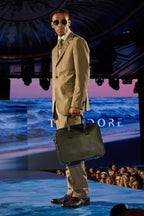 Beige Pinstripe Suit, a model walks the runway past an ocean-themed backdrop with a black bag