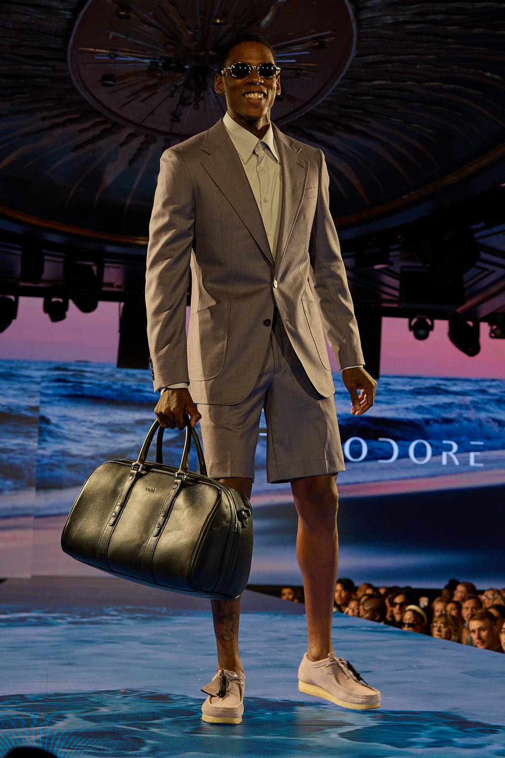 Lavender Haze Suit, a model walks toward camera smiling on the runway