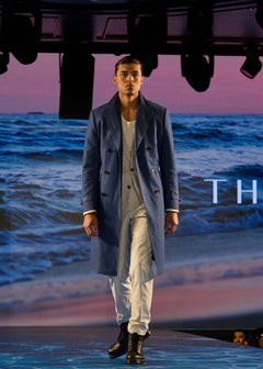 Grey Jersey Stretch Suit styled with an overcoat, runway shot against an ocean backdrop