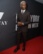 The Brown Capper Three Piece worn alone, model adjusting a jacket cuff on a red carpet