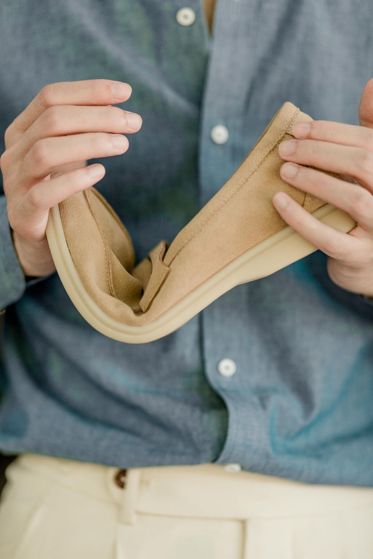 The Echelon Beige Suede Penny Loafer held and flexed to show the sole