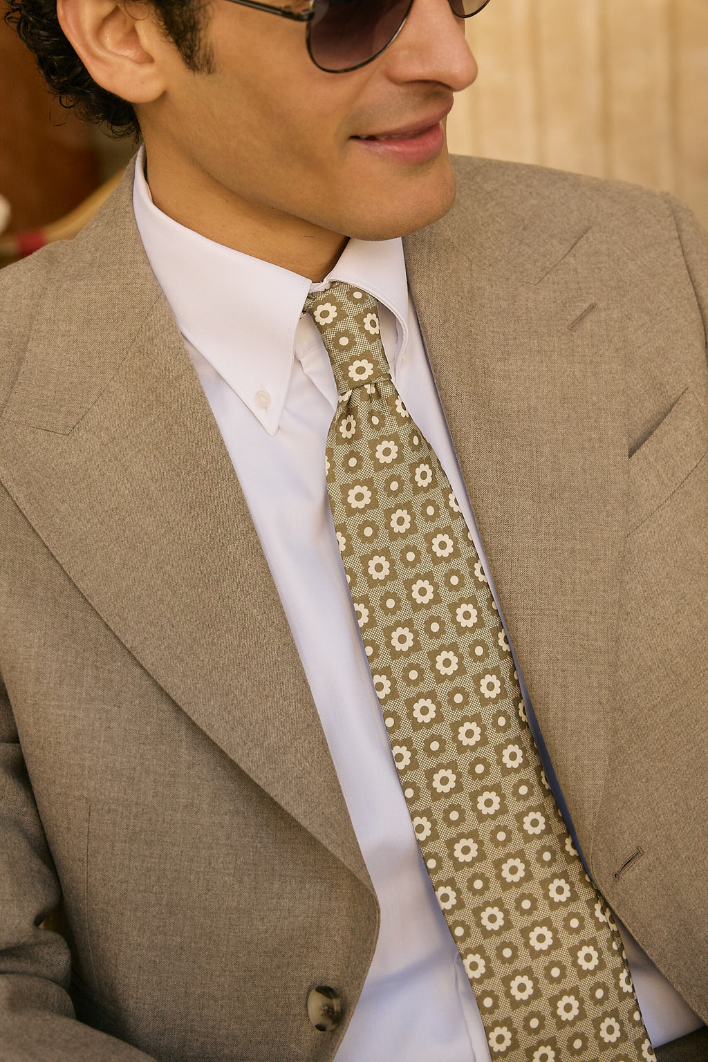 Close-up of the Ashford suit lapel and patterned tie, model glancing sideways
