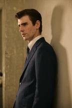 The Stratford Navy Check Suit worn by a model in side profile against a wall