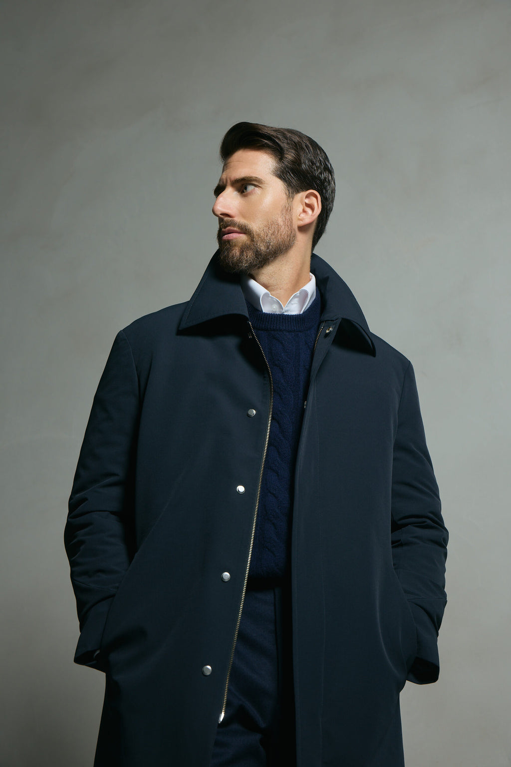 The Ellison Tech Navy Coat worn by a model with the collar up, looking aside