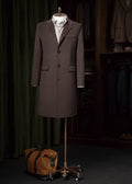 Baker Street Coffee Cashmere Blend Overcoat on a stand beside a tan duffel bag