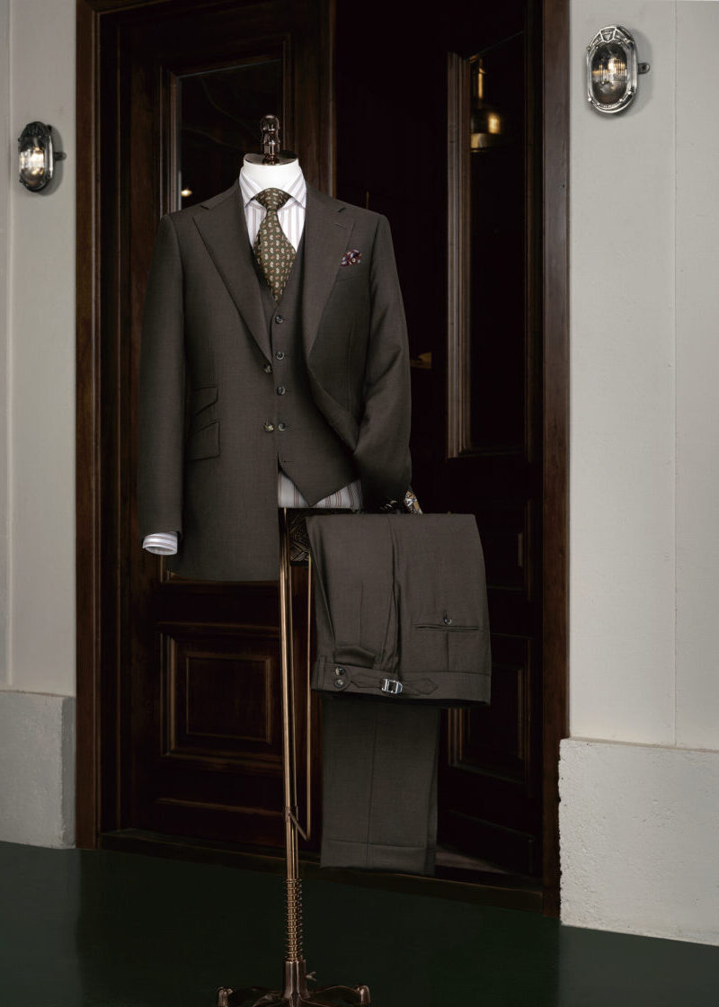 Waterloo Brown Suit displayed on a tailor's dummy at a wooden entrance