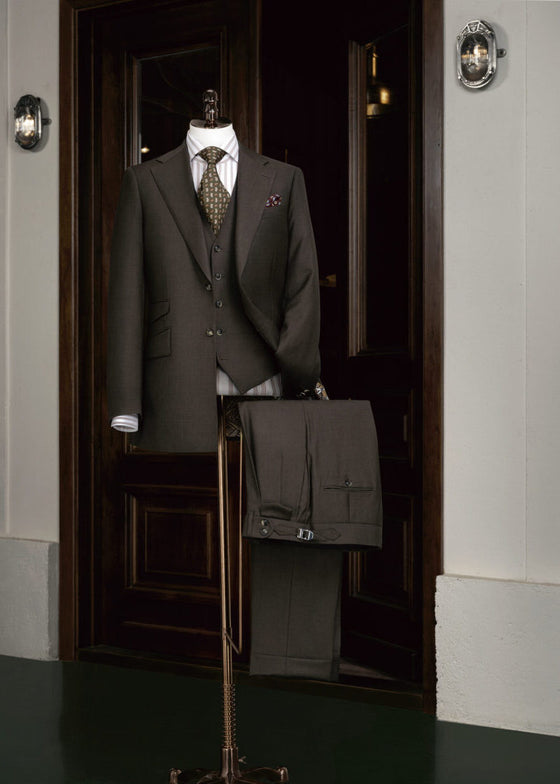 Waterloo Brown Suit displayed on a tailor's dummy at a wooden entrance