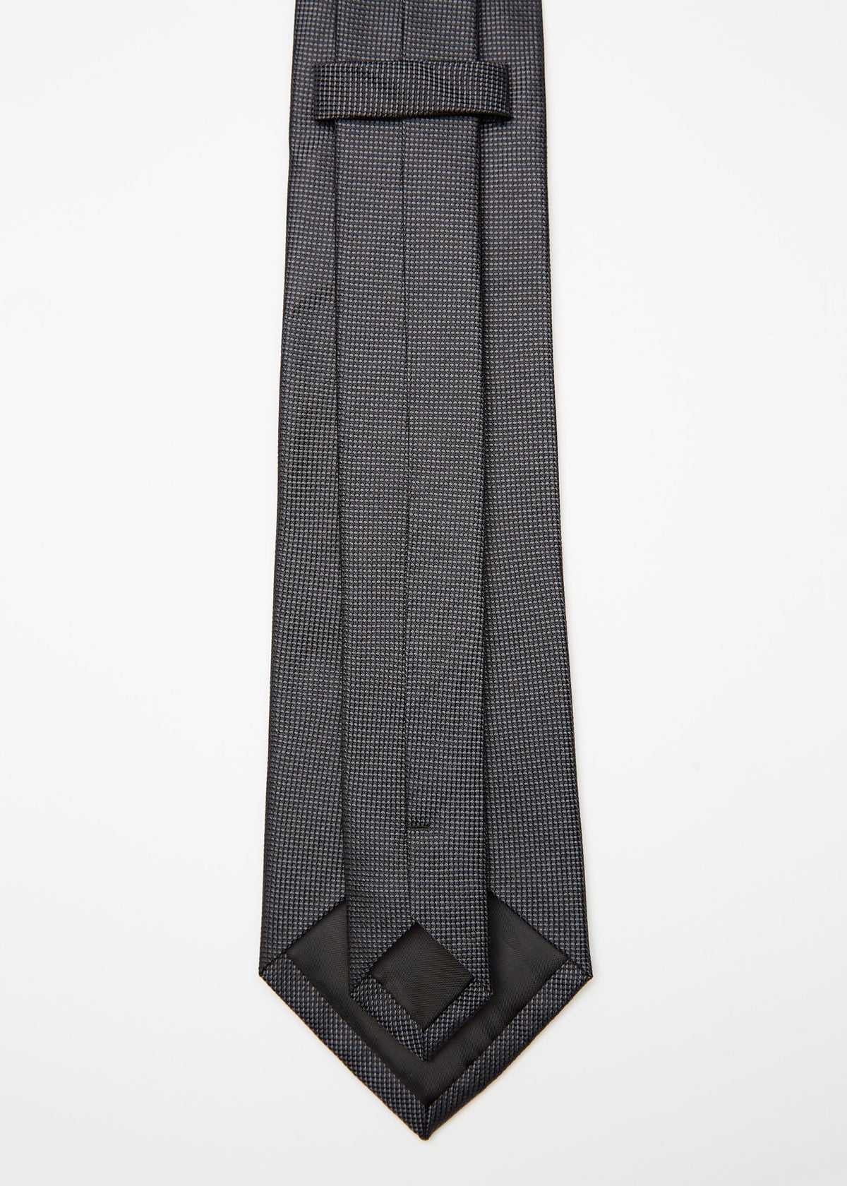 Amsterdam Silk Tie in black micro pattern, angled flat lay with tip turned back