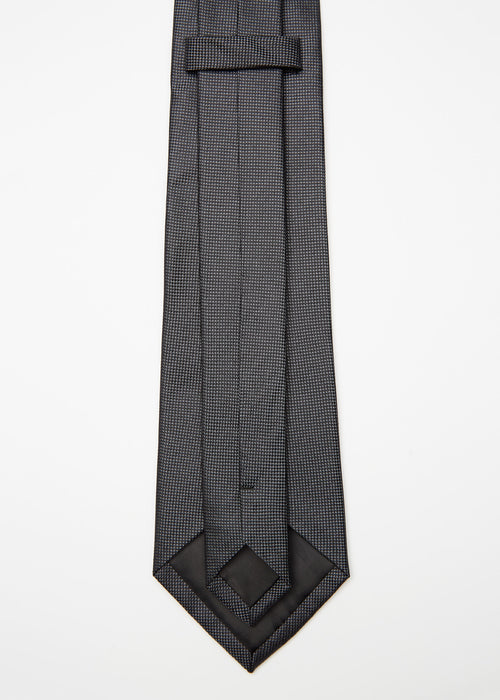 Amsterdam Silk Tie in black micro pattern, angled flat lay with tip turned back