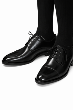 Soft leather split-toe black derby shown worn on a model's feet, both shoes visible