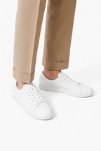 Zante White Sneaker worn by a model with cuffed camel trousers, studio background