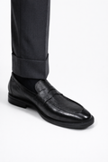 Gaston Black Pebbled Deerskin Penny Loafers worn on a model, close-up with trouser cuff