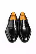 The Manor Black Penny Loafer pair shown front-on with shoe trees, product shot