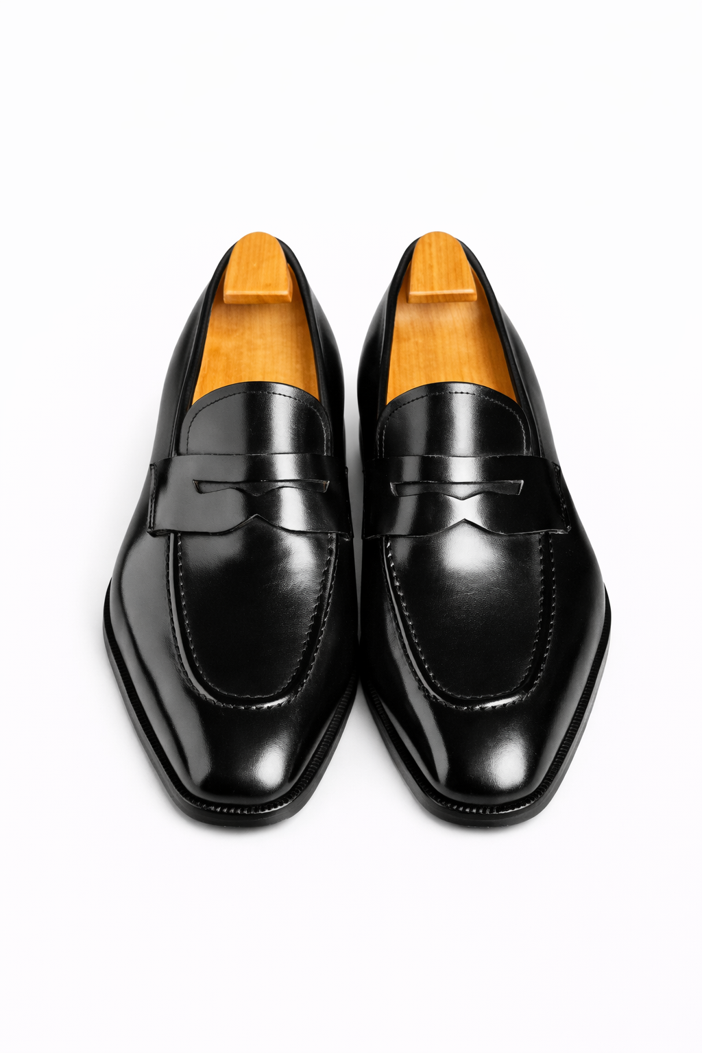 The Manor Black Penny Loafer pair shown front-on with shoe trees, product shot