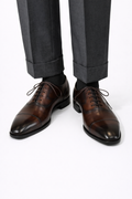 The Konbanwa Square-Toe Triple-Stitched Brown Oxford worn on a model with cuffed grey trousers