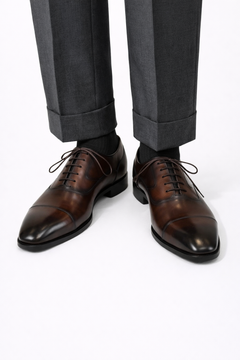 The Konbanwa Square-Toe Triple-Stitched Brown Oxford worn on a model with cuffed grey trousers