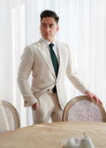 The Orchard Cream Linen Blend Suit worn with a green tie, model indoors by a table