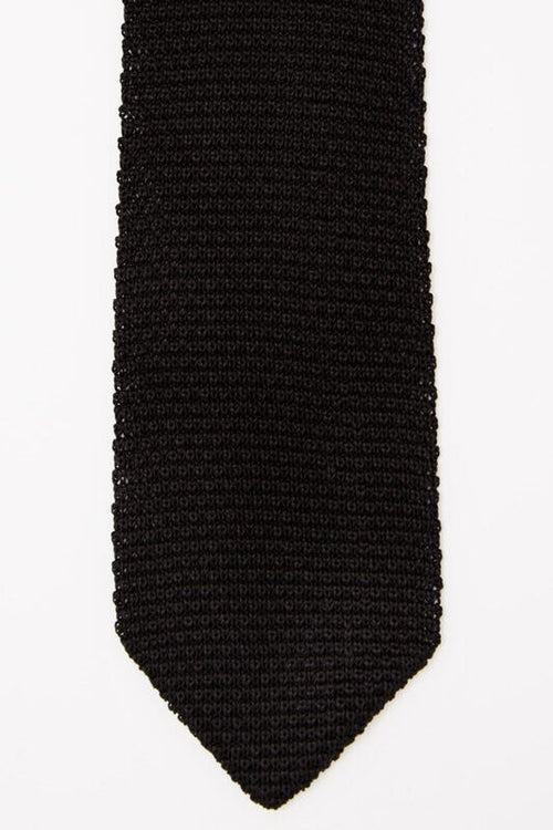 Hong Kong Tie in knit black silk, close-up of the pointed tip on a white background