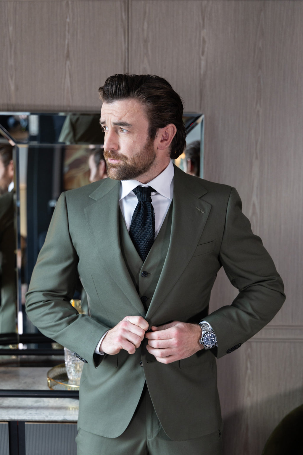The Olive Horizon Suit worn by a model buttoning the jacket