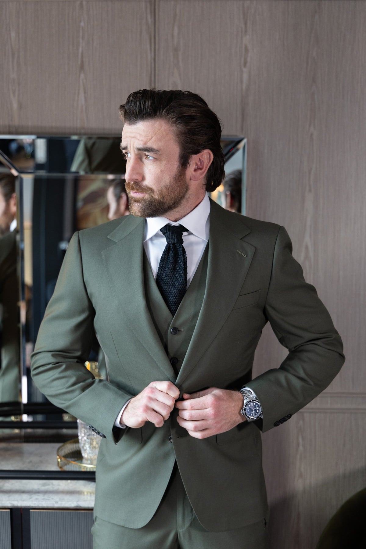 The Olive Horizon Suit worn by a model buttoning the jacket