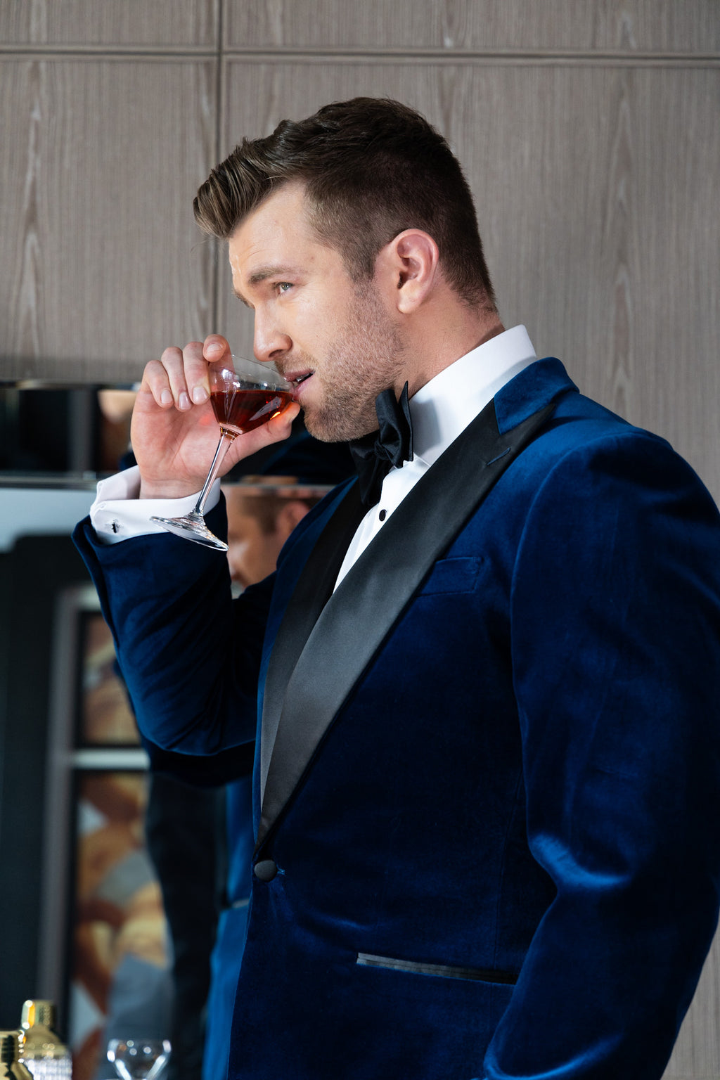 Velvet Noir navy tuxedo worn on a model, side profile holding a drink