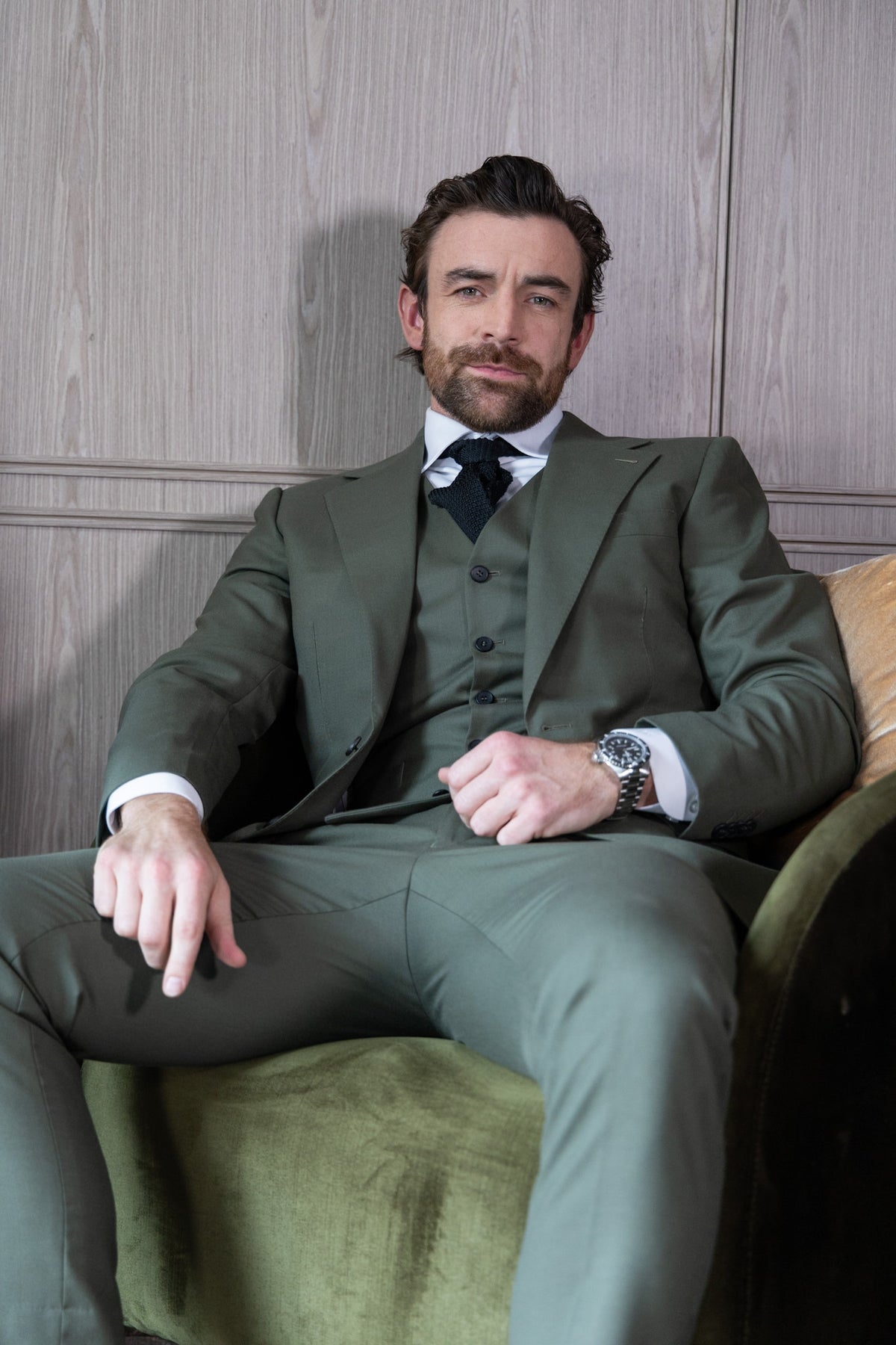 The Olive Horizon Suit worn by a model seated, facing the camera
