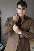 Close-up of a model in the Modern Mellow brown suit, hand adjusting the collar