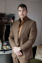 Modern Mellow brown suit on a model beside a bar cart, glass of whisky nearby