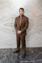 Modern Mellow brown suit on a model standing against an indoor marble wall