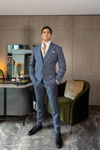 The Vivid Voltage Steal Grey Suit worn by a model beside a green armchair