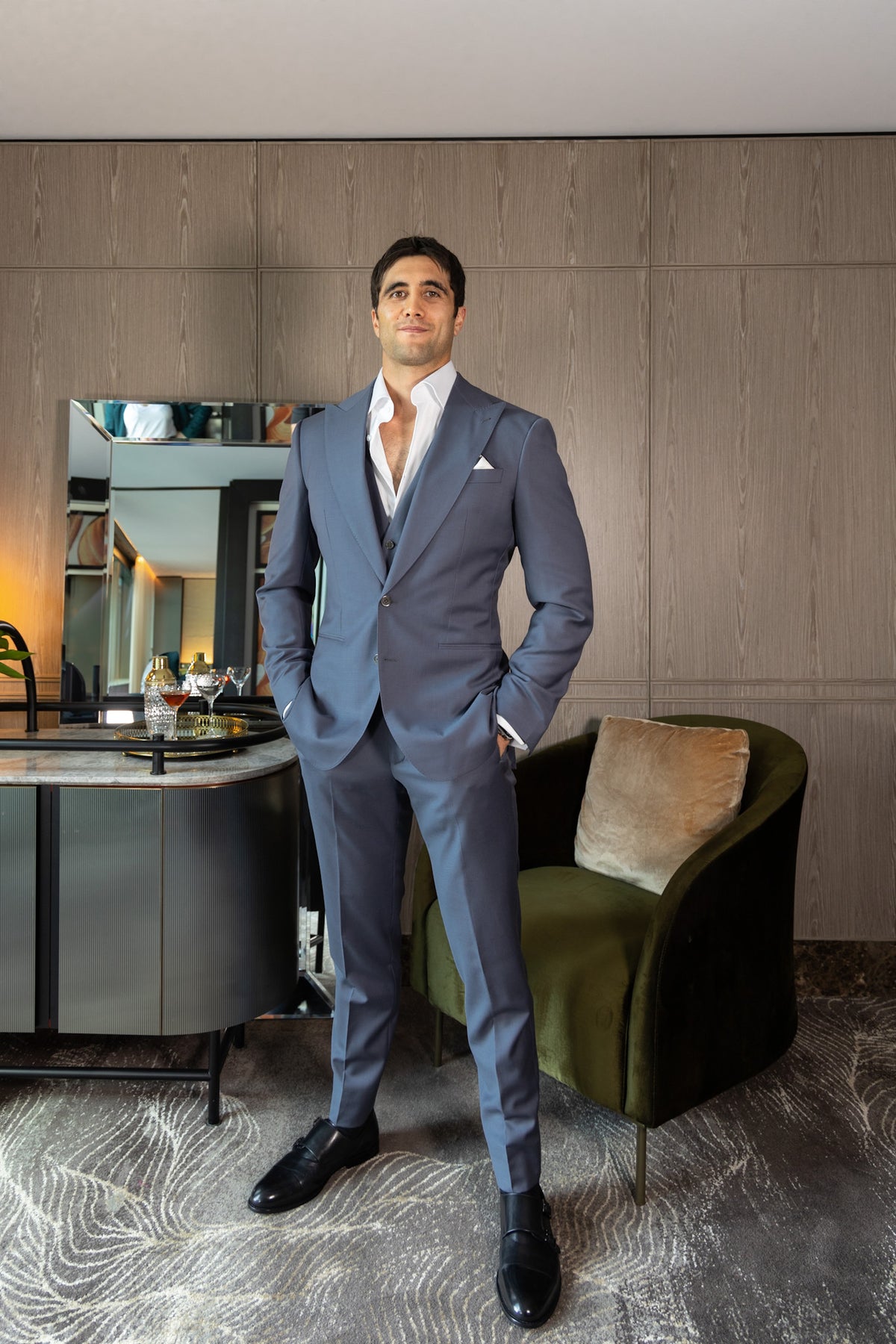 The Vivid Voltage Steal Grey Suit worn by a model beside a green armchair