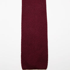 Paris Silk Knit Tie in burgundy, laid in a soft curve on a plain background