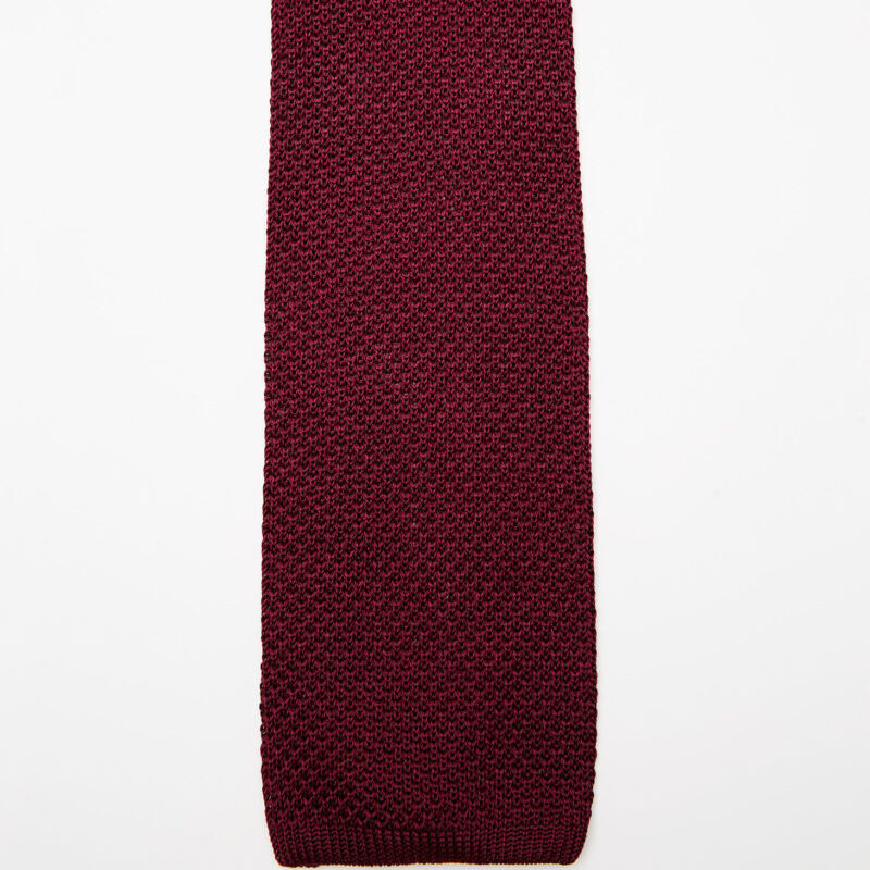 Paris Silk Knit Tie in burgundy, laid in a soft curve on a plain background