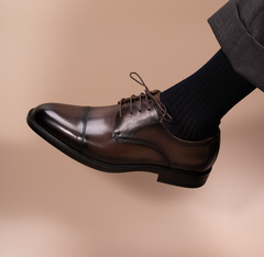 Soft leather split-toe brown derby shown worn on a model's foot, angled view