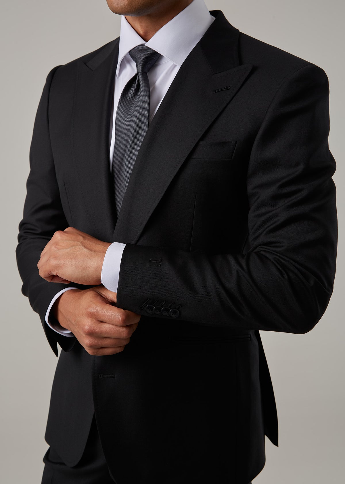 Midnight Milano The Ultimate Black Suit, close crop of the torso with hands adjusting the cuff