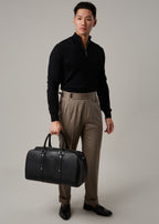 Christian travel bag held by a model wearing a black quarter-zip jumper