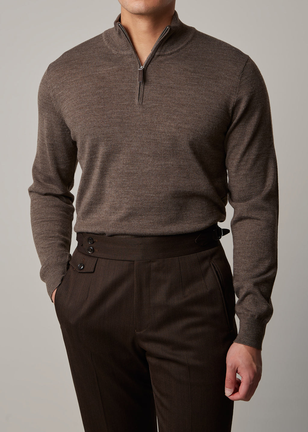 Cosmo quarter-zip jumper in brown, worn on a model with hand in pocket